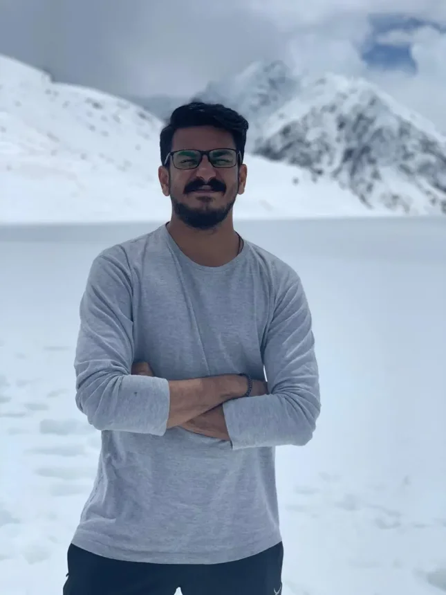 Khurram Adhami, founder of Pebble, standing with his arms folded in front of snow-covered mountains
